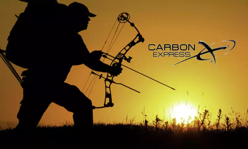 silhouette of man carrying a compound bow with carbon express logo